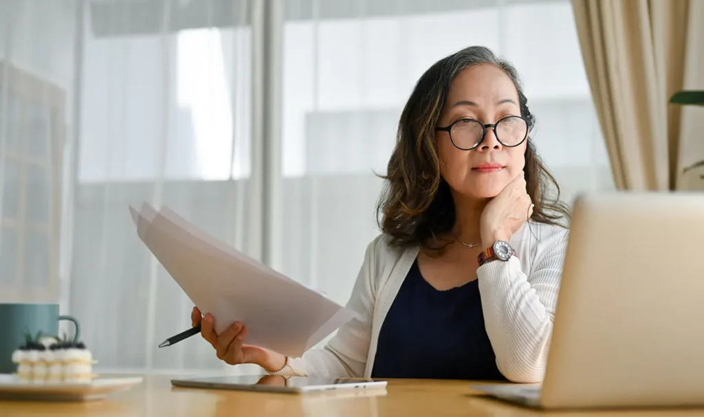 Woman reviewing papers & laptop